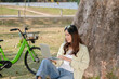 © MIND AND I - Woman working at park using laptop.