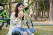 © MIND AND I - Young woman eating meal at park.