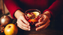 Hands of woman holding cup of hot mulled wine for Christmas