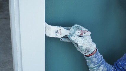 Wall Mural - A worker is painting the walls of the house with a primer using a paint roller.