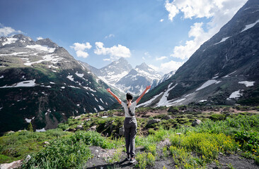 Wall Mural - Travel by Swiss Alps. Young woman enjoying the mountains view with hands up.