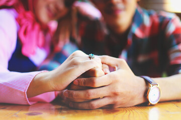 closeup of a couple's hands holding each other, with a blurred background