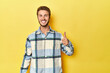 © Asier - Young Caucasian man on a yellow studio background smiling and raising thumb up