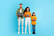 European family of three using different gadgets laptop, tablet computer and smartphone, standing over blue background