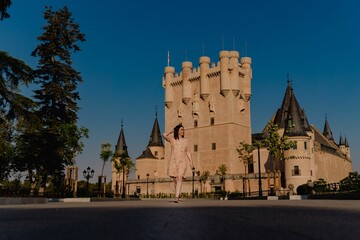 Poster - Young female posing at the historic Alcazar Castle against a clear sky, Segovia, Spain