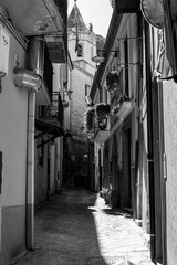 Wall Mural - Grayscale of a narrow street with traditional Italian buildings on a sunny summer day in Lauria
