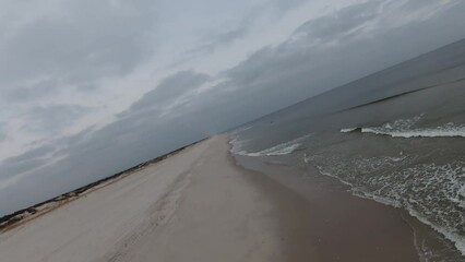 Wall Mural - Aerial of the calm sea waves and the sandy shore under the gloomy sky