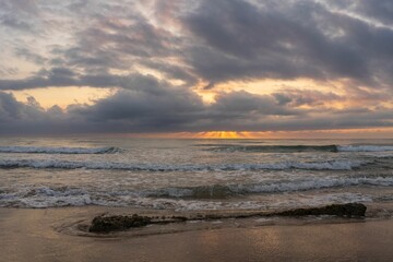 Wall Mural - spectacular sunrise on the beach of gandia with pink and orange sky and rocks near the water. spain.