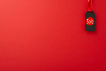 Wall Mural - Prudent buyer Black Friday inspiration. Overhead photograph featuring sale sticker on price tag on a red surface, providing space for promotional content