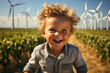 Portrait of happy little boy in corn field with wind turbines in background. 