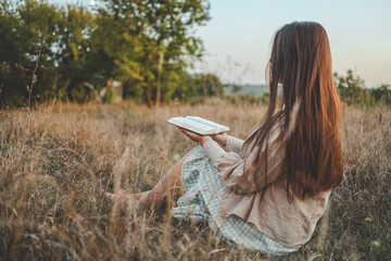 Girl with a Bible in her hands in nature, evening prayer and worship