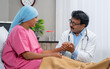 © WESTOCK - Indian doctor consoling cancer patient by giving confidence while holding hands at hospital - concept of emotional support, medical treatment and Compassionate Care