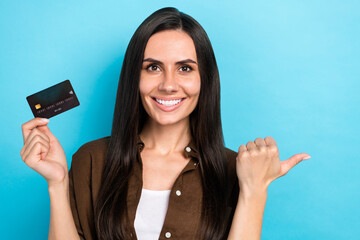 Sticker - Photo of adorable positive girl dressed brown shirt rising bank card thumb empty space isolated blue color background