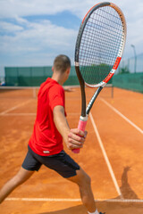 young professional player coach on outdoor tennis court practicing strokes with racket and tennis ball playing against opponent