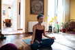 © Marko Geber - Young Caucasian woman meditating and doing yoga in the living room at home