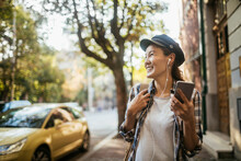 Happy young Asian woman using a smartphone while walking in the city