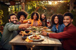 © Bojan - Happy multiracial friends toasting and having fun together during meal on a patio at sunset.