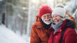 Senior couple laughing and enjoying life outdoors in winter. Beautiful woman and handsome man dressed in warm winter clothes. Blurry forest background.