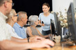 © JackF - Middle-aged woman teacher making explanation to elderly people sitting at computer table in IT training room