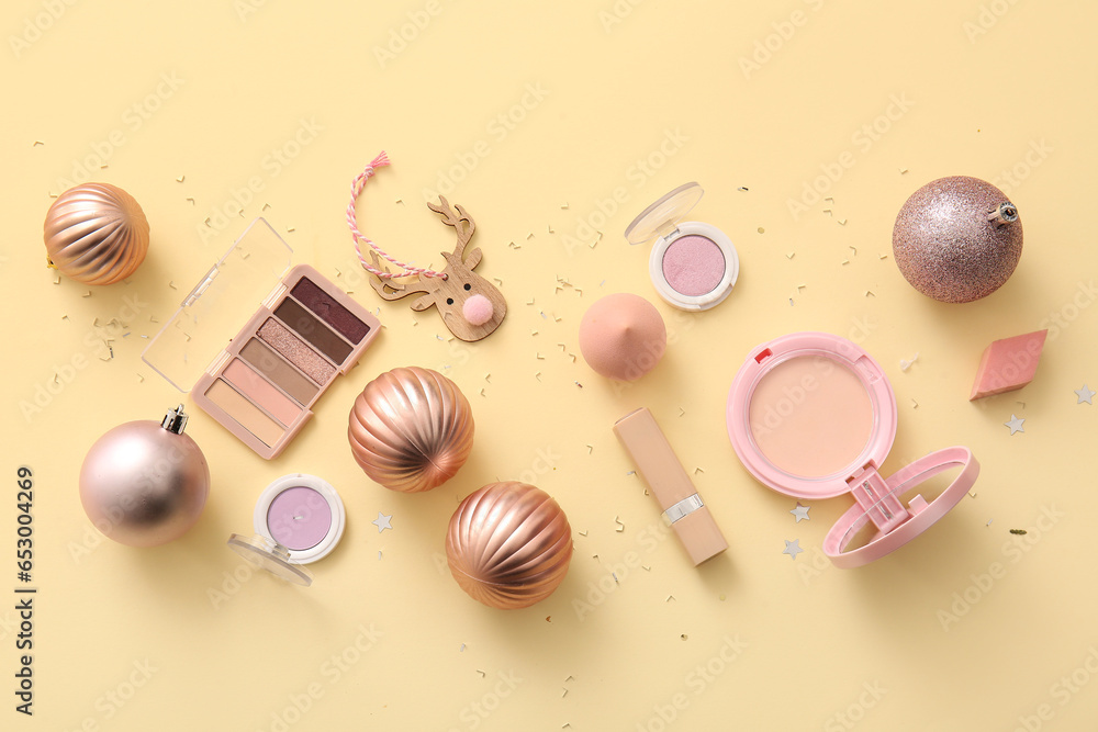 Composition with decorative cosmetics and Christmas decor on beige background