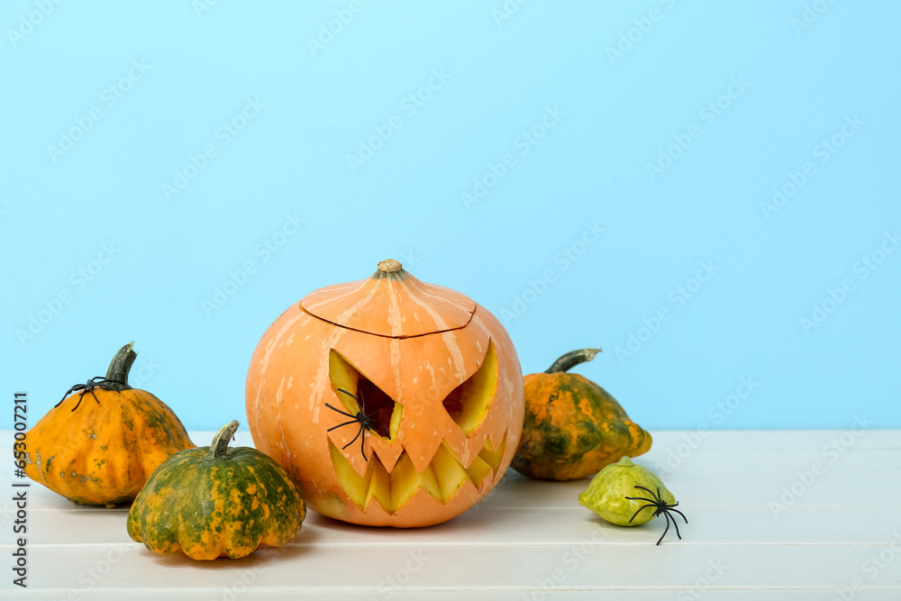 Carved Halloween pumpkin and squashes on light wooden table