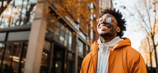 black person with glasses and afro hair looking up with yellow jacket and white sweatshirt laughing 
