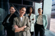 © CarlosBarquero - Team portrait of diverse female professionals confident posing outside business center. Group of smiling empowered formal working women looking at camera outdoor office. Photo of elegant co-workers.