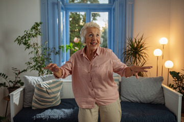 Happy elderly grandma is dancing at her home