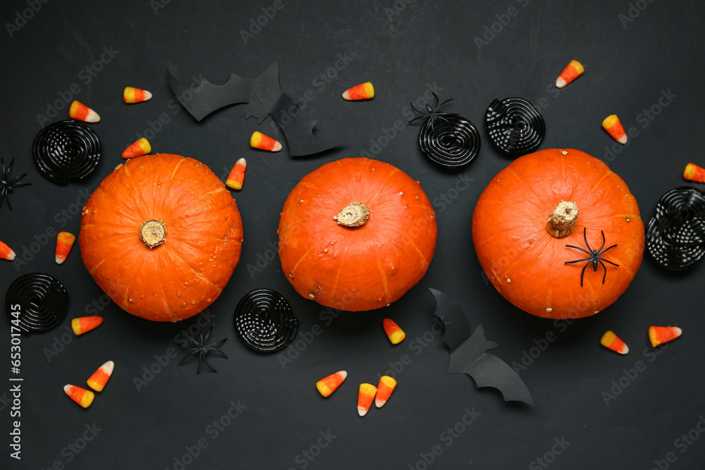 Halloween composition with pumpkins and sweet candies on black background