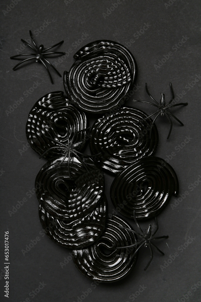 Halloween composition with licorice candies and spiders on black background