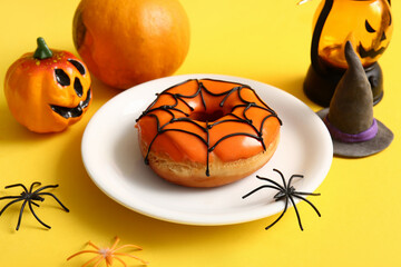 Wall Mural - Plate of tasty donut with decorations for Halloween on yellow background