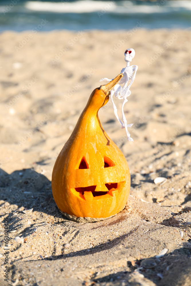 Carved pumpkin for Halloween with skeleton on beach
