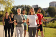 © New Africa - Group of happy people practicing Nordic walking with poles in park