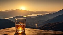 A Whiskey Glass And A Bottle On A Bar Table In The Background Are Mountains And A Sea Of Mist At Sunset.