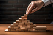 strategy enhancement scenario where a person is carefully placing wooden blocks to build a pyramid, symbolizing the meticulous planning and execution required in business