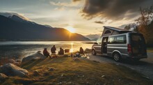 Family Camping Car Go On Holiday In A Campervan, Parked Next To The River, With The Mountains Behind The Sunset.