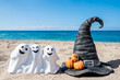 Halloween beach with three ghosts and witch hat background