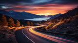 Fototapeta  - Winding lakeside road at night, bathed in the ethereal glow of moving car lights and a surreal sunset
