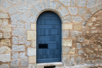 Ancient wooden blue door in old stone arch wall on historical facade building