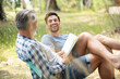 © auremar - two jovial men relaxing in the countryside with a book