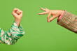Poster. Two hands, female showing support fist gesture, male demonstrate zero sign isolated on green background.
