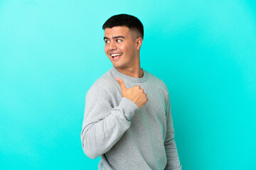 Wall Mural - Young handsome man over isolated blue background pointing to the side to present a product