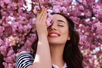 Poster - Beautiful woman near blossoming sakura tree on spring day