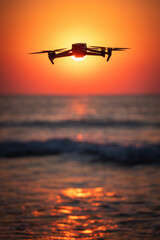 Canvas Print - Ocean beach sunrise and flying drone against sun and sea horizon