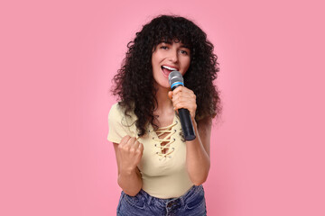 Poster - Beautiful young woman with microphone singing on pink background