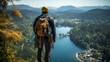Ausgerüsteter Bergsteiger mit Klettergurt und Rucksack steht an einer Kante vor einer Bergkulisse mit See an einem schönen Sommertag