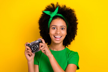 Wall Mural - Portrait of positive lovely person toothy smile have good mood hands hold photo camera isolated on yellow color background