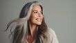 A joyful, beautiful, aged woman with delicate flawless skin, gray ash-colored hair enjoying the result of cosmetic procedures.