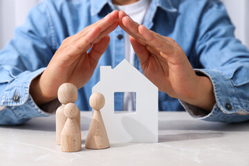 White house, wooden figures and hands on light background