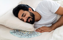 Smiling Young Indian Man Sleeping With Bunch Of Cash Dollars Under Pillow